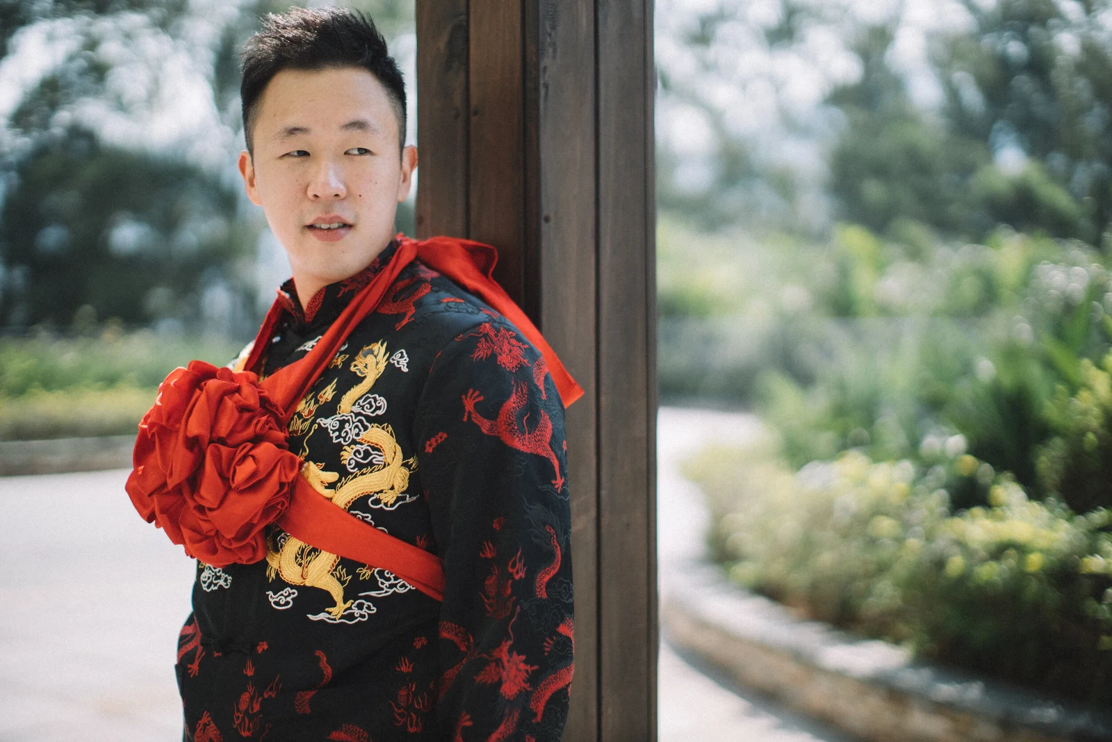 穿中式禮服的新郎站在戶外,胸前佩著大紅花