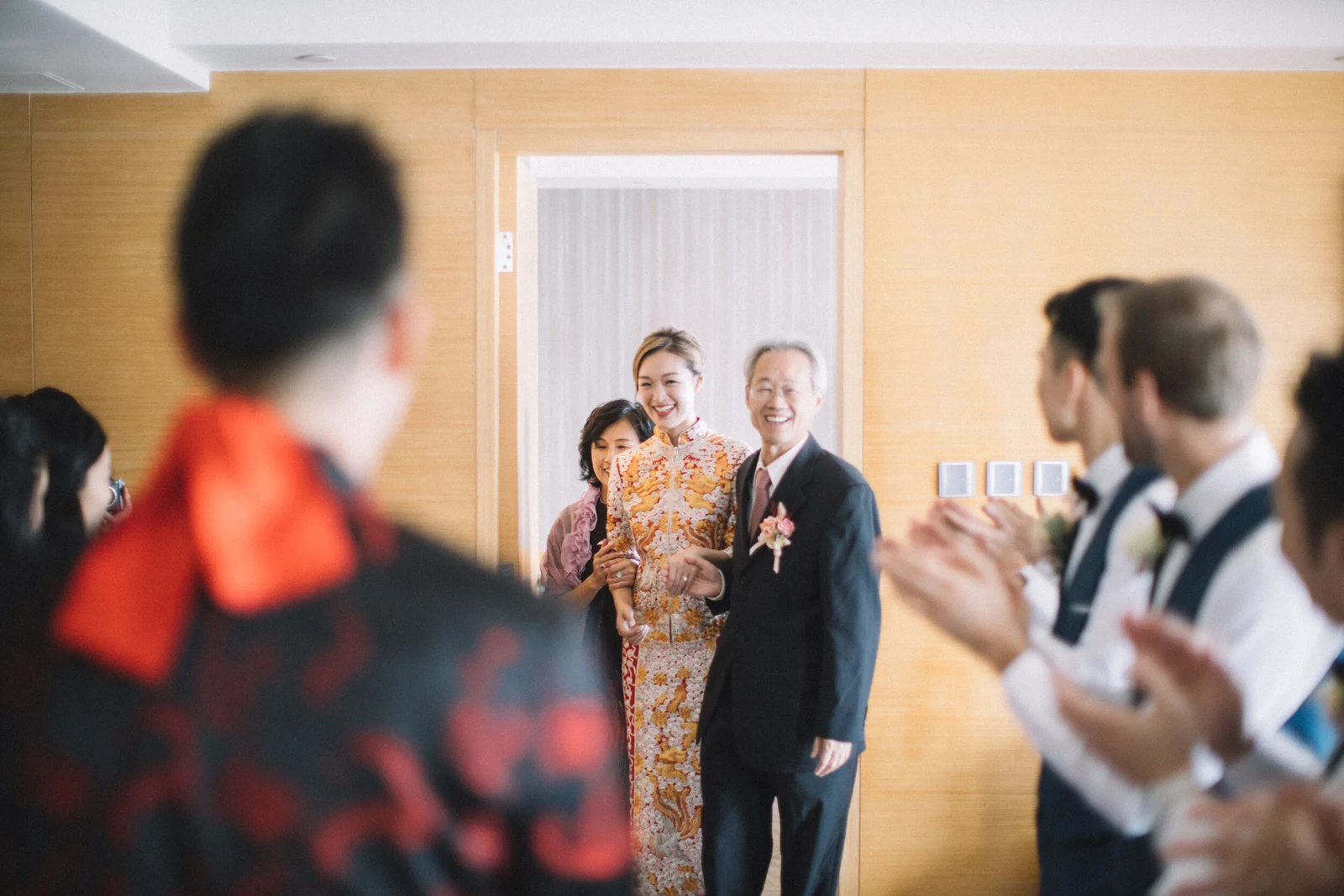 新娘與長輩站在房內,親友在兩旁鼓掌