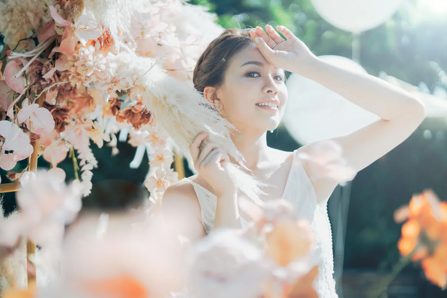 花藝旁的新娘抬手遮擋陽光,背景帶有暖色光斑