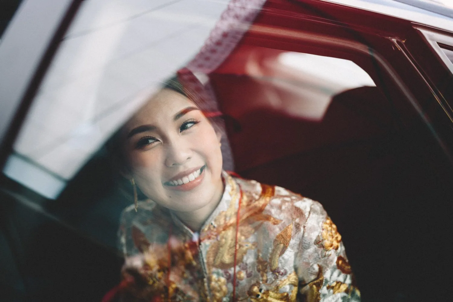 Asa 穿裙褂坐在婚禮車內微笑，透過車窗倒影拍攝的新娘人像