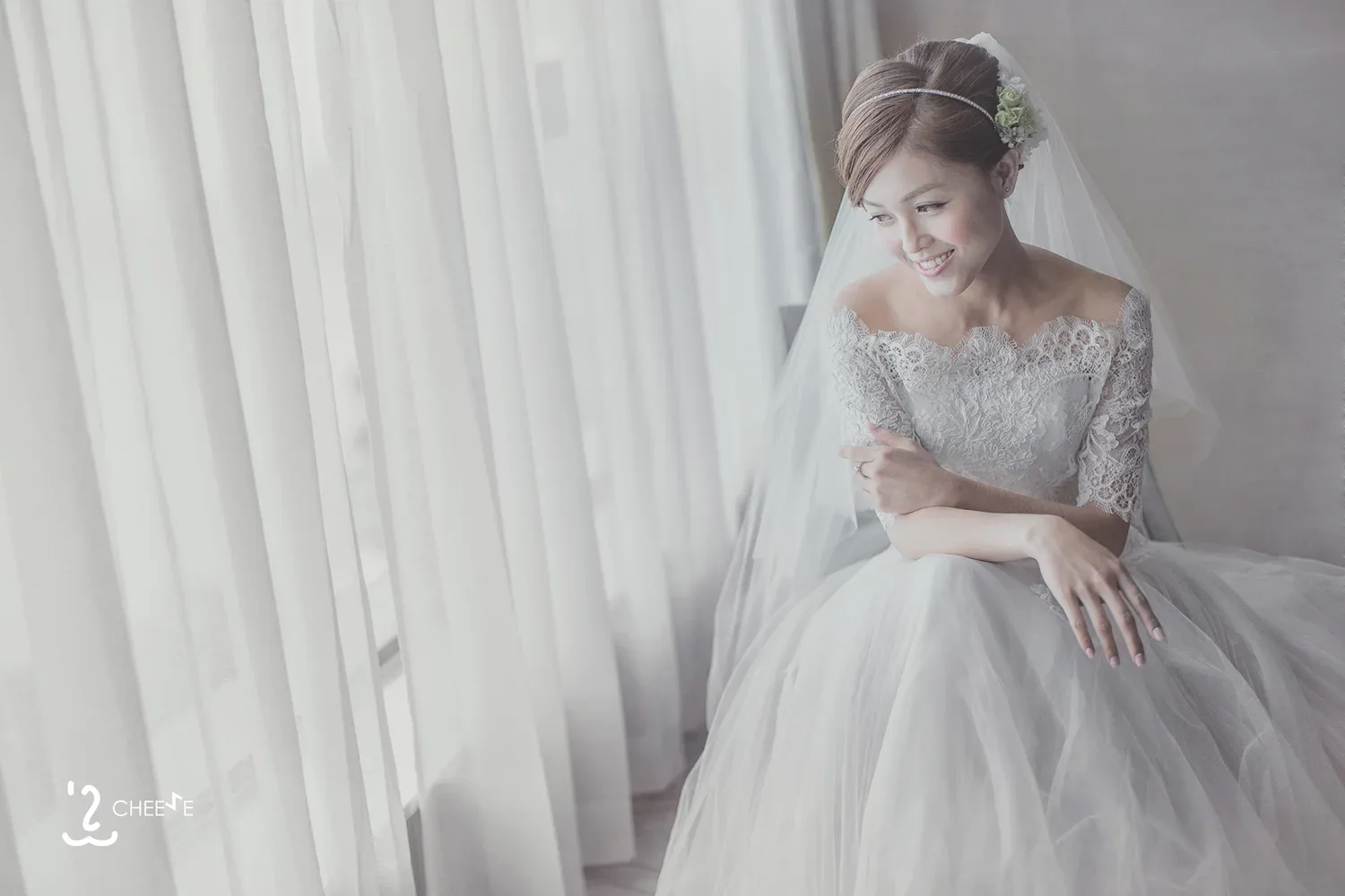 長袖蕾絲婚紗新娘坐在窗邊,低頭微笑