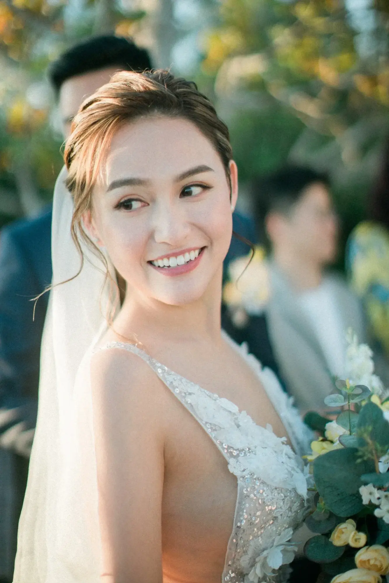 新娘在戶外回眸微笑,髮髻旁別着花飾