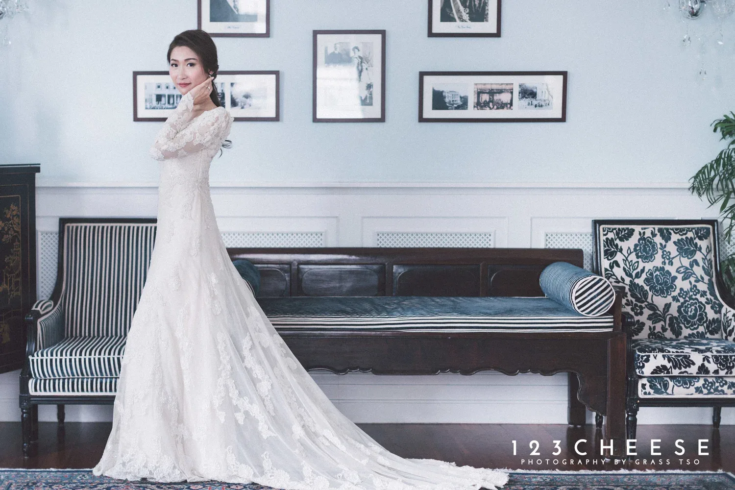 長袖蕾絲婚紗新娘站在沙發前,裙襬沿地面展開