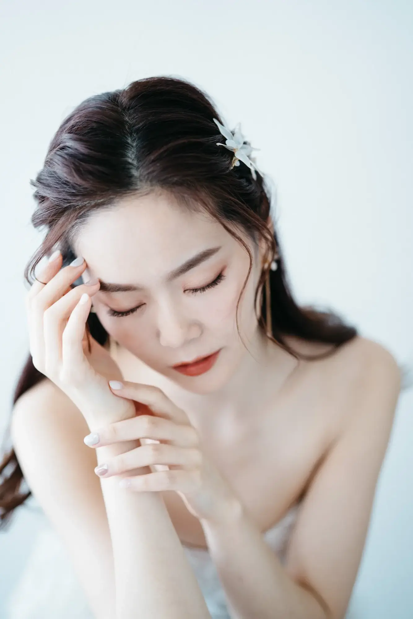 新娘低頭閉眼,指尖輕觸額角
