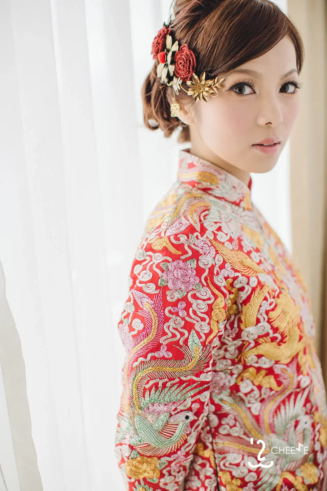 金紅裙褂新娘在窗邊回眸,髮髻旁插着紅金花飾