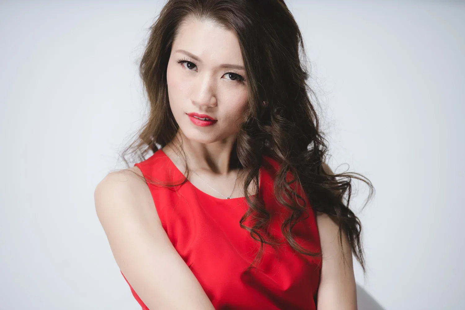 穿紅色禮服的女子望向鏡頭,捲髮垂在肩上