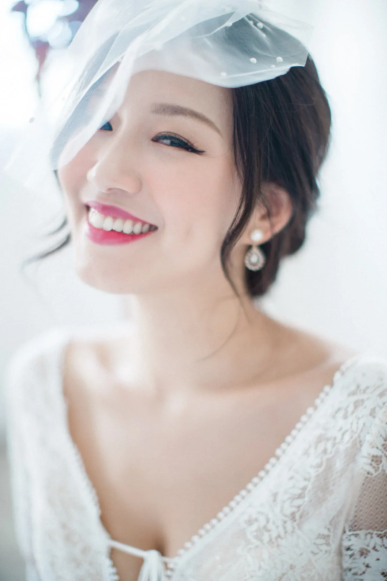 頭紗下的新娘抬頭大笑,白色耳飾垂在耳邊